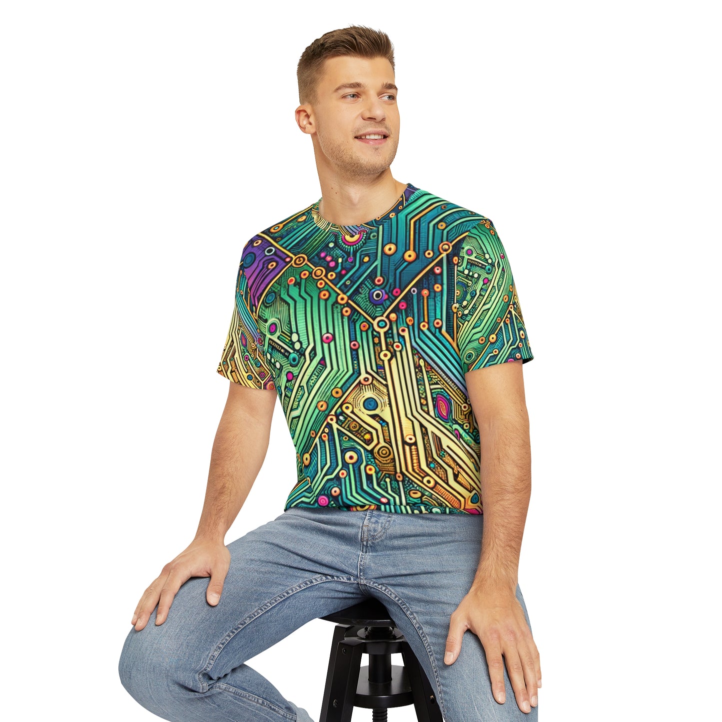 Front view of the Circuit Synapse Fiesta Crewneck Pullover All-Over Print Short-Sleeved Shirt circuit print pattern green blue yellow red black white blast of colors paired with casual denim pants worn by a white man sitting on a stool chair